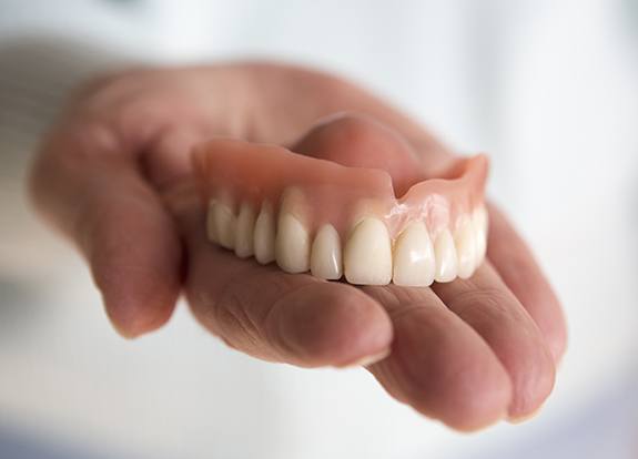 Hand holding set of dentures