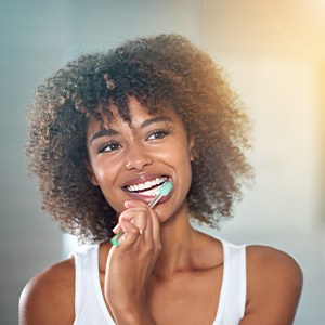 Woman brushing teeth at bathroom mirror