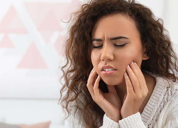 Woman in need of emergency dentistry holding jaw