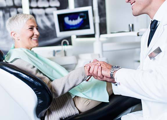 Smiling woman shaking the hand of her Grand Prairie implant dentist