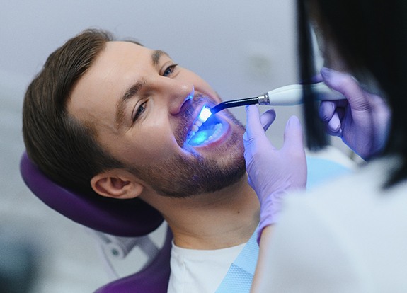 Woman in dental chair smiling at dentist putting cloth over her shirt