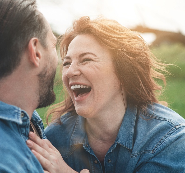 Older woman with dental implants in Grand Prairie smiling with husband