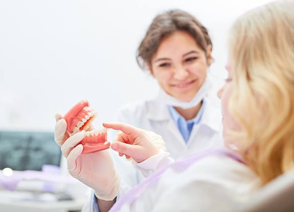 Dentist holding model of dentures in Grand Prairie 