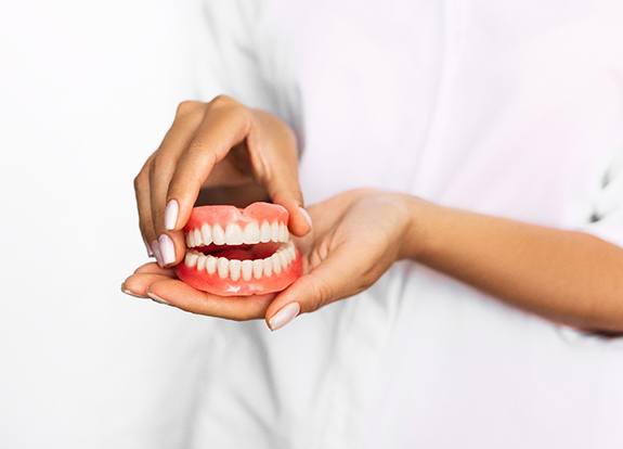 Closeup of dentist holding set of full dentures in Grand Prairie 
