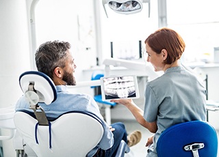 Dentist smiling at patient while reviewing X-ray