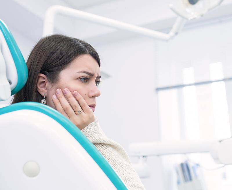 Woman in need of emergency dentistry holding jaw in pain