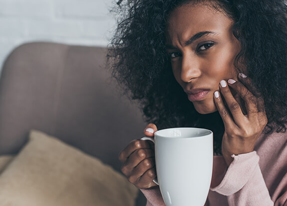 Woman holding jaw before emergency dentistry treatment