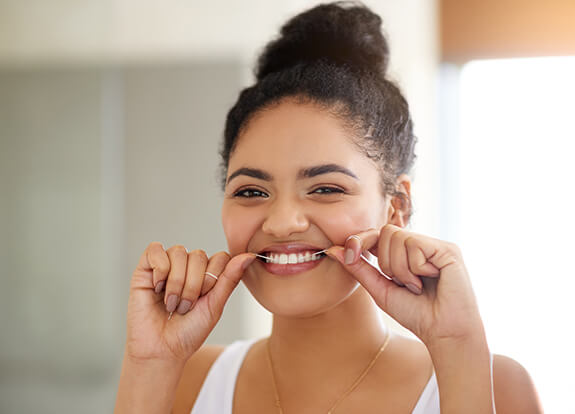 Woman flossing teeth to prevent dental emergencies