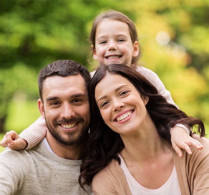 Family of three smiling outdoors