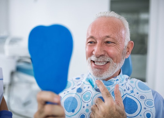 senior man admiring his new smile with dental implants in Grand Prairie 