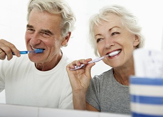 senior man and woman brushing their teeth together 