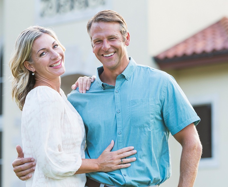 Man and woman smiling after replacing missing teeth