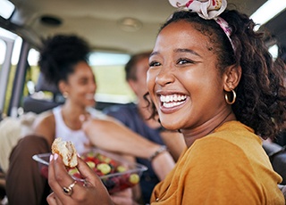 Woman smiling while eating lunch in car with friends