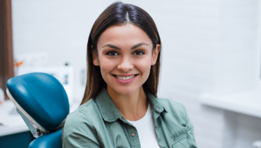 Woman in dental chair smiling after preventive dentistry visit