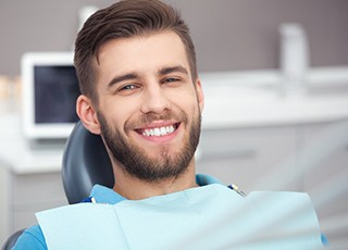Male dental patient smiling while sitting in a dental chair