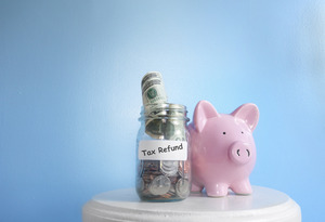 Piggy bank next to a full jar that says “Tax Refund”