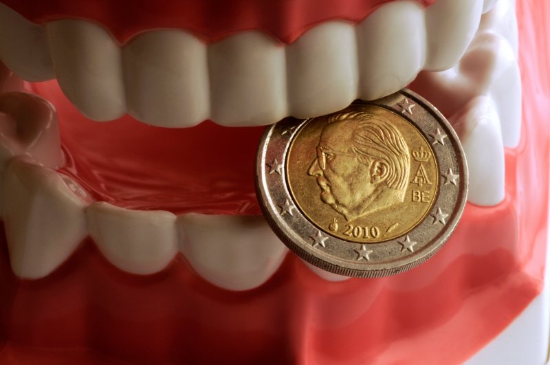 Model of teeth with good oral health biting a coin